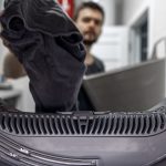 Homme chargeant un lave-linge, illustrant le sujet « Pièces détachées de lave-linge : réparer ou remplacer ? Les signes clés ».