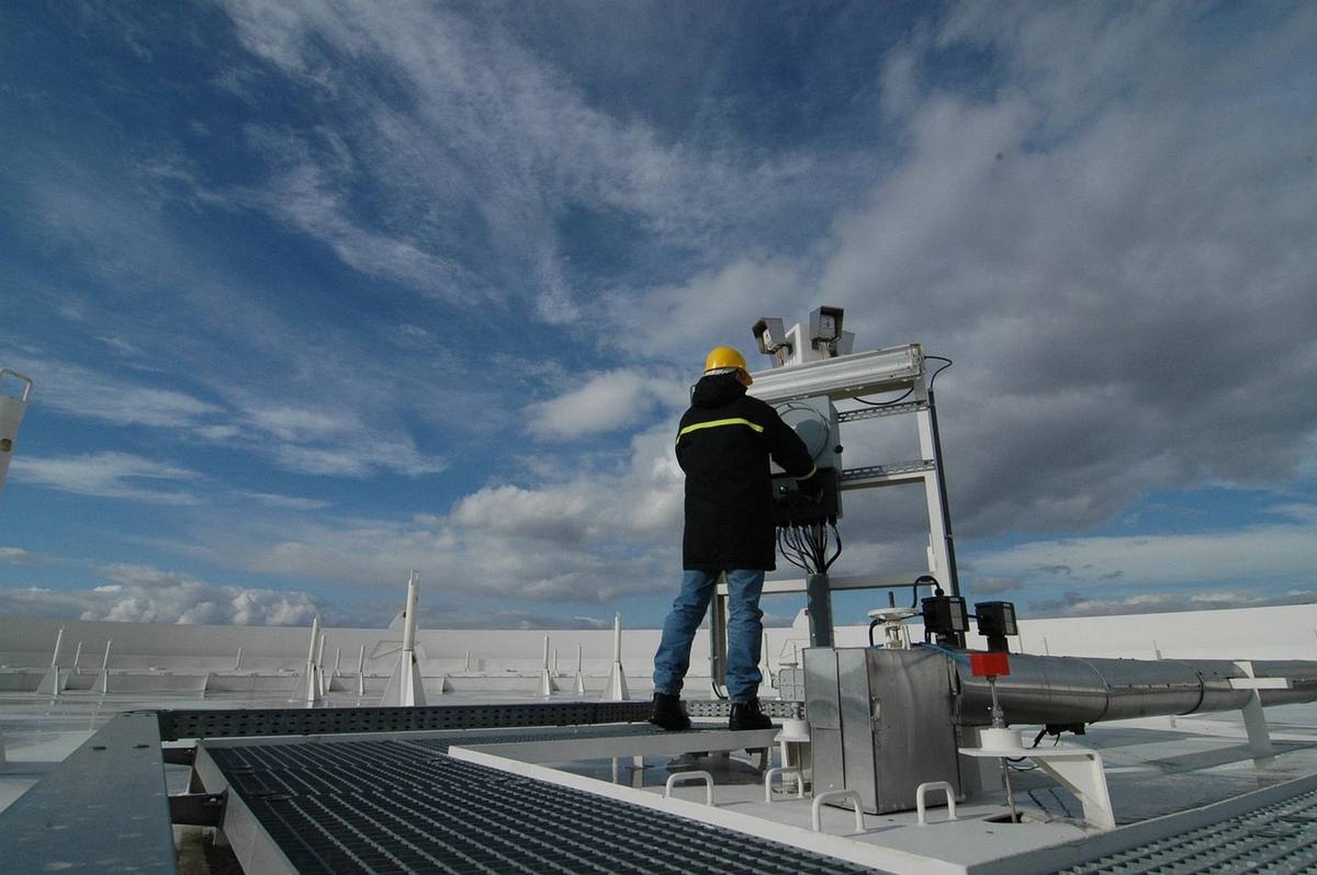 Un technicien ajuste une installation sur une plateforme sous un ciel couvert Un technicien ajuste une installation sur une plateforme sous un ciel couvert