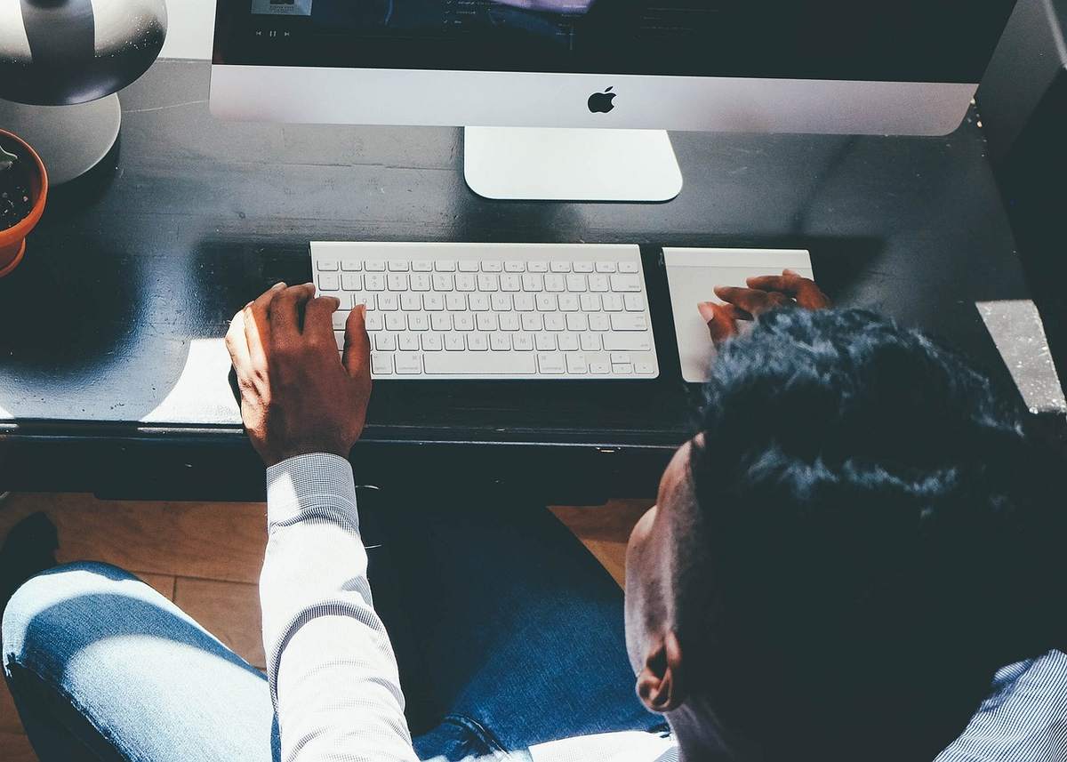 Une personne travaille sur ordinateur depuis une position assise Une personne travaille sur ordinateur depuis une position assise