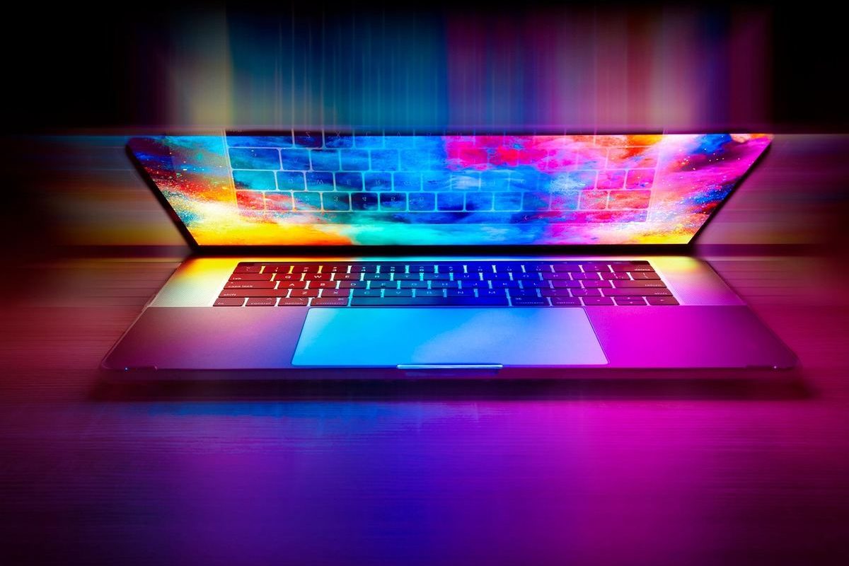 Un ordinateur portable ouvert projette des couleurs vives sur le bureau