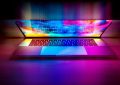 Un ordinateur portable ouvert projette des couleurs vives sur le bureau